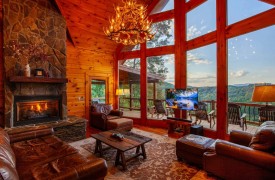 Riverview Lodge | Cabin Rentals of Georgia | Spacious Living Area with two story open ceiling, antler chandelier, leather furnishings, stone gas log fireplace