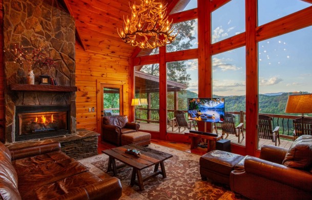 Welcome to Riverview Lodge Riverview Lodge | Cabin Rentals of Georgia | Spacious Living Area with two story open ceiling, antler chandelier, leather furnishings, stone gas log fireplace
